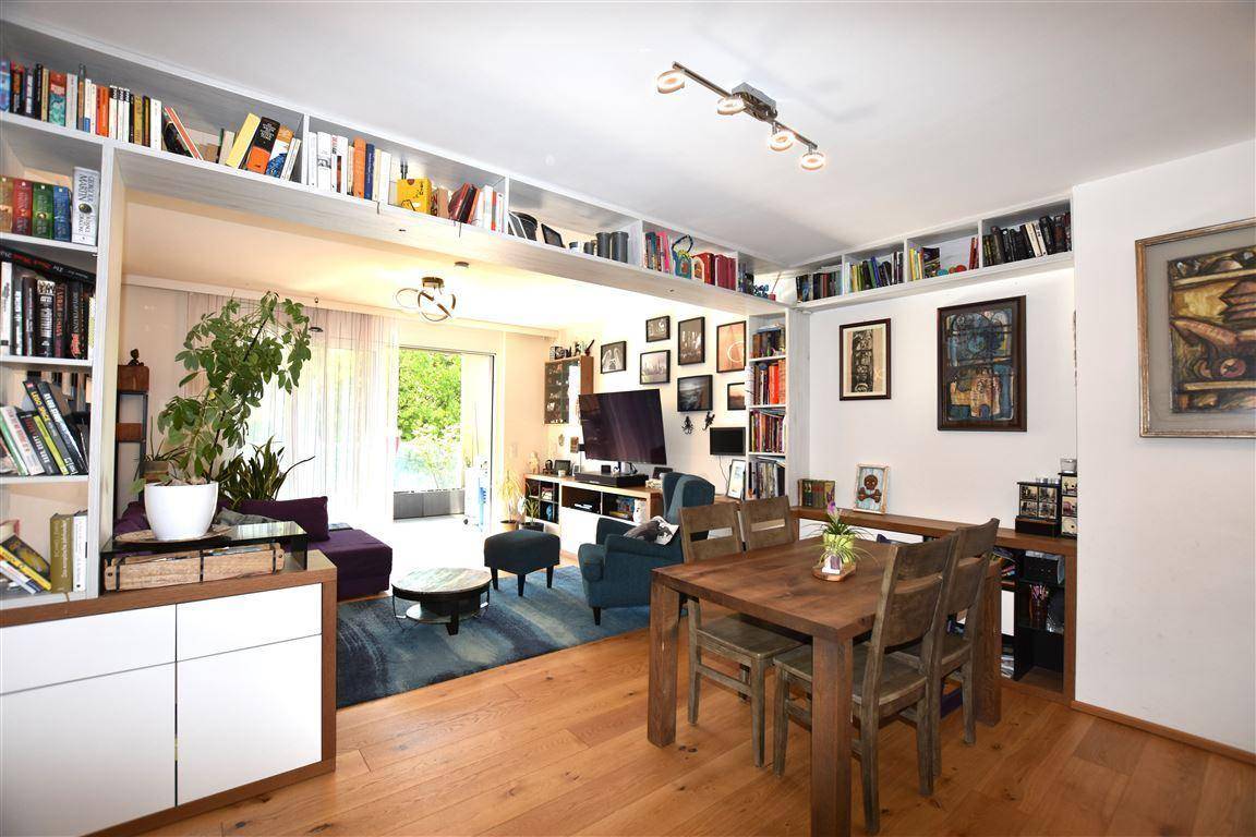 Offener Wohn- und Essbereich mit Holztisch, Bücherregalen und hellem Ambiente.