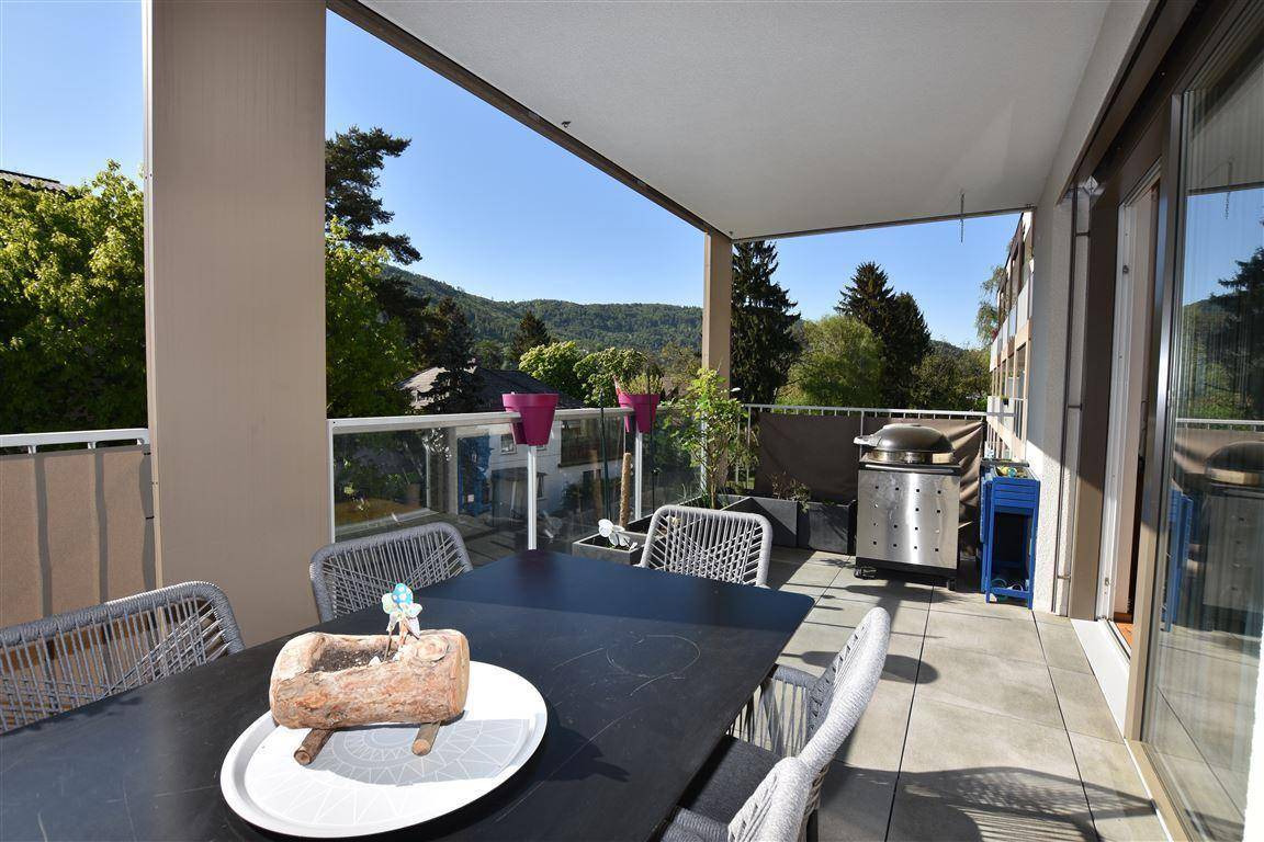 Geräumiger Balkon mit Esstisch, Grill und weitem Blick auf die grüne Landschaft.