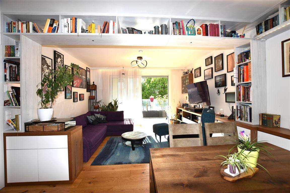 Heller Wohn- und Essbereich mit Holztisch, Bücherregalen und Zugang zum Balkon.