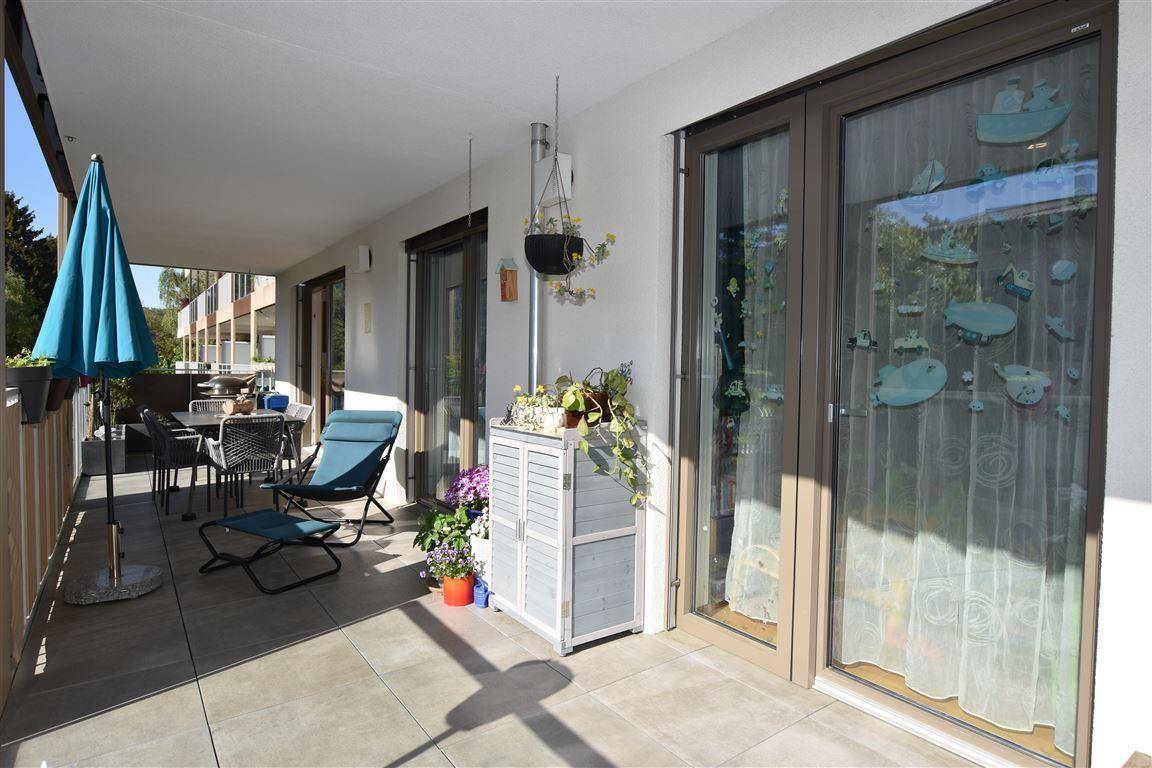 Geräumiger Balkon mit Sitzgelegenheiten, Sonnenschirm und Blick auf die Umgebung.
