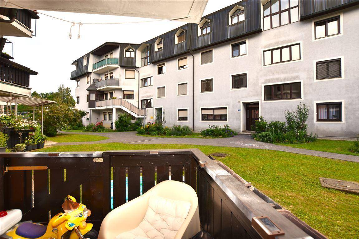 Blick vom Balkon auf den gepflegten Gemeinschaftsgarten und die Wohnanlage.