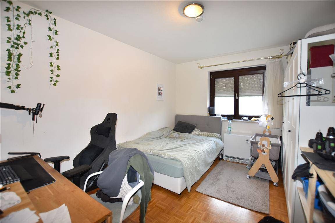 Schlafzimmer mit Bett, Schreibtisch, Kleiderschrank und Fenster, ausgestattet für Komfort.