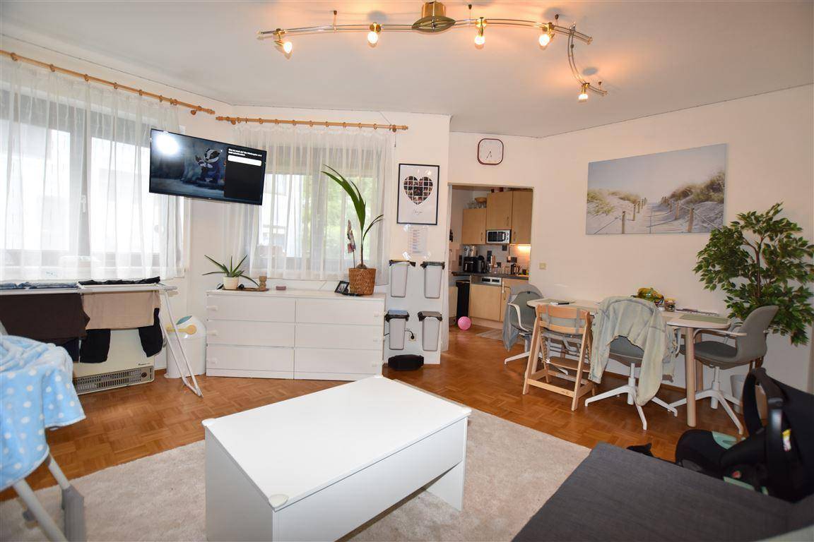 Heller Wohn-Essbereich mit Fernseher, Esstisch und Sofa, durch große Fenster gut belichtet.
