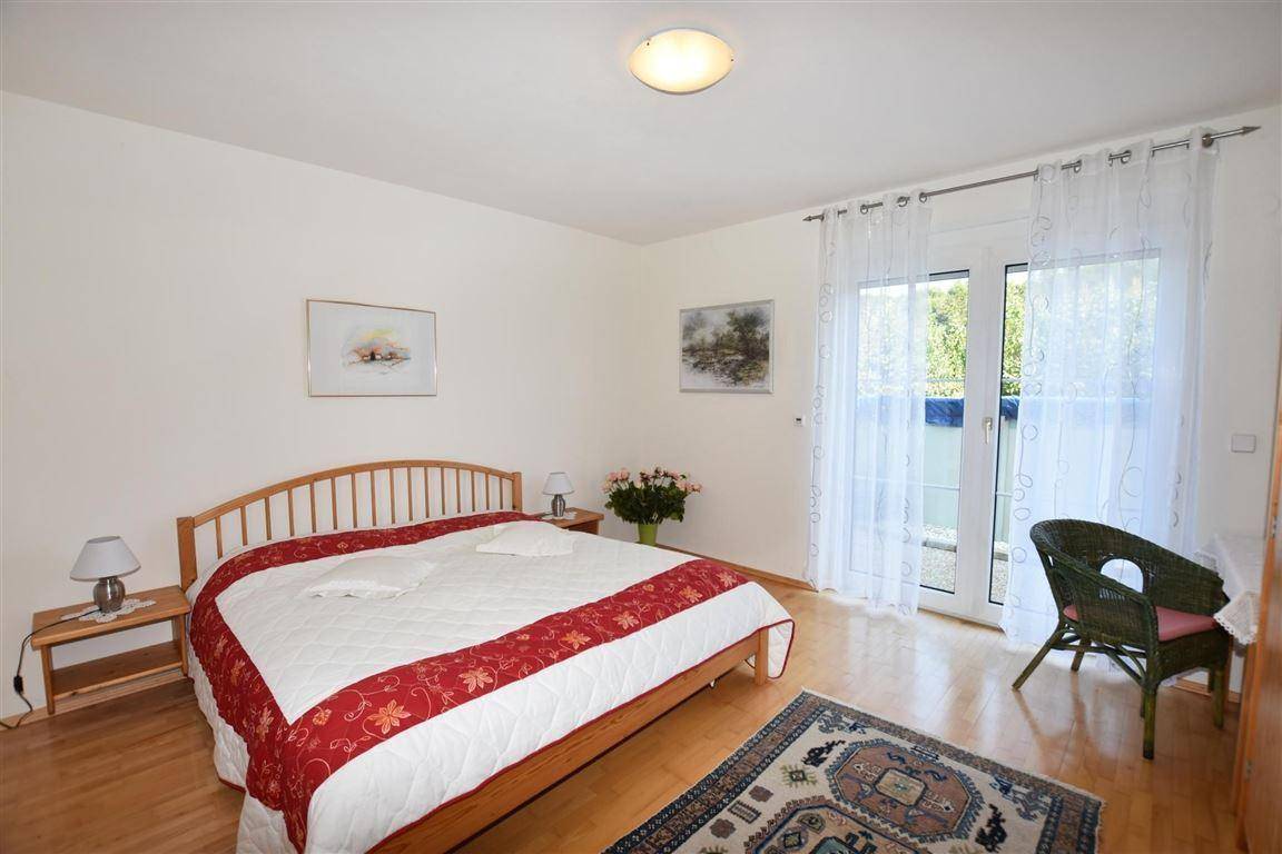Gemütliches Schlafzimmer mit Doppelbett, Holzboden und Zugang zu einem Außenbereich.