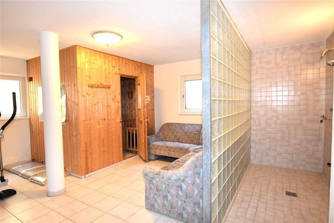 Privater Wellnessbereich mit Sauna, Duschbereich und Sitzgelegenheiten für Entspannung.