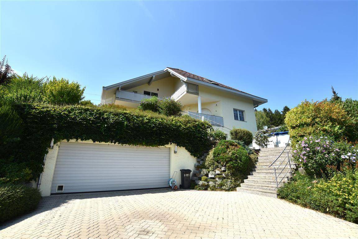 Ansicht des Hauses von unten mit Garageneinfahrt und Treppe zum Eingangsbereich.