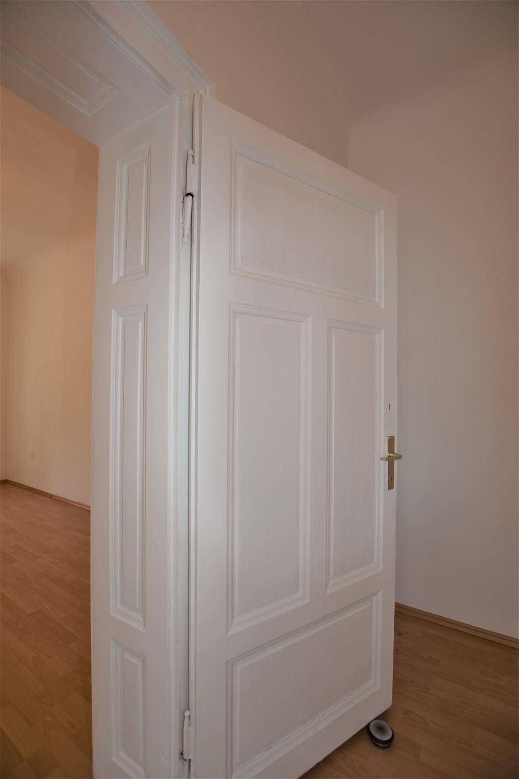 Weiße Flügeltür in einem hellen Raum mit Holzboden.