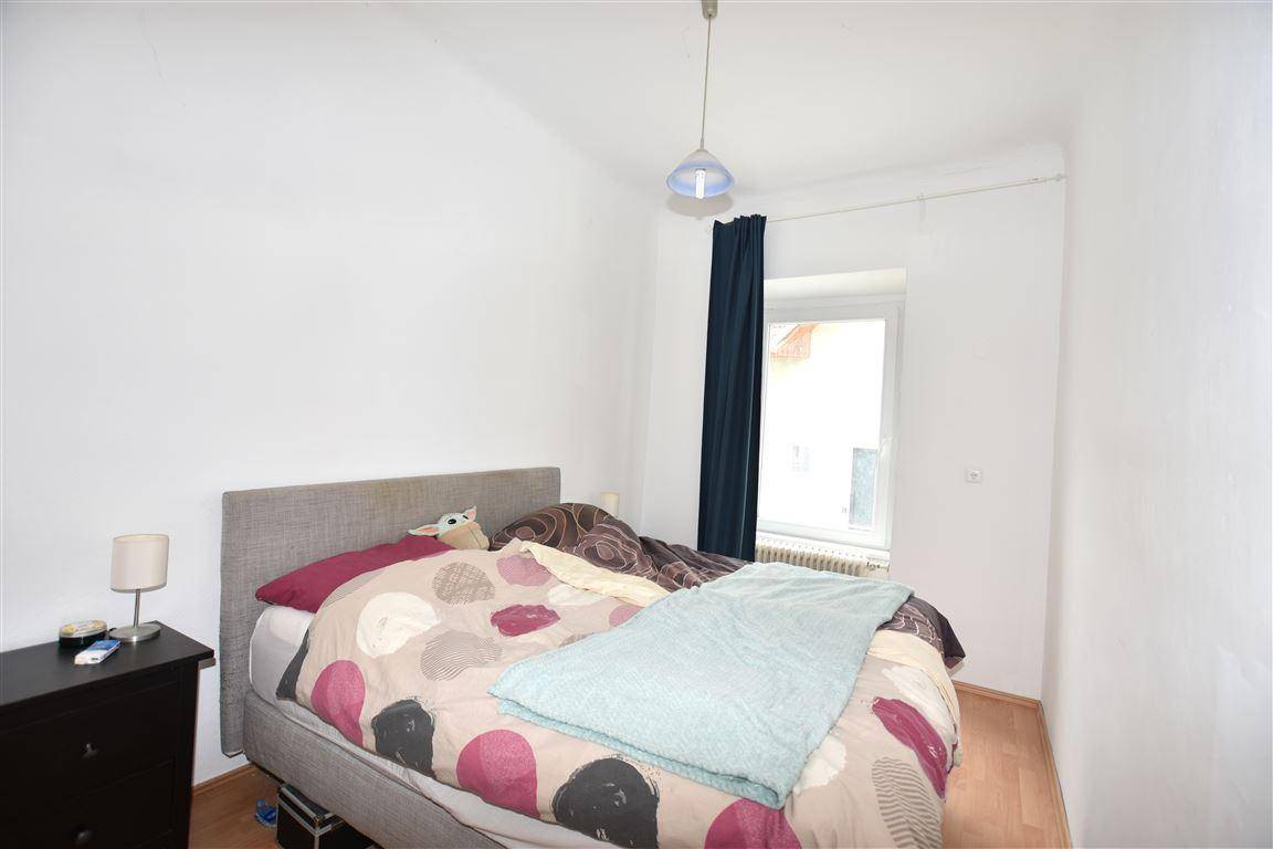 Schlafzimmer mit Doppelbett, Nachttisch und Fenster.