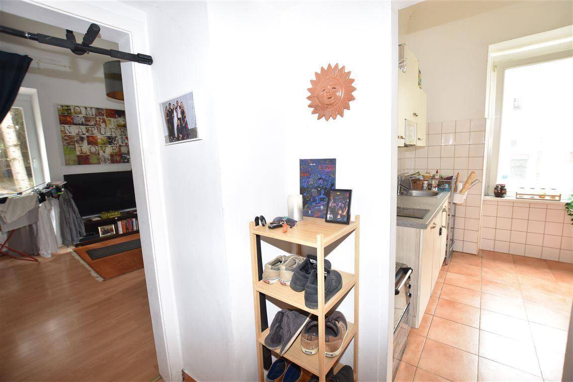 Flur mit Schuhregal, der zum Wohnzimmer und zur Küche führt.
