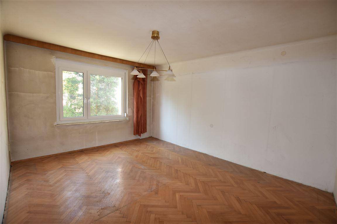 Leeres Zimmer mit Fischgrätparkett und großem Fenster, bereit zur individuellen Gestaltung.