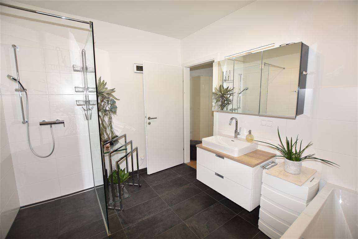 Modernes Badezimmer mit ebenerdiger Dusche, Einzelwaschbecken und dunklen Bodenfliesen.