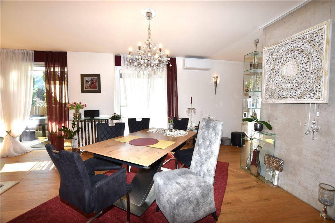 Eleganter Essbereich mit großem Holztisch, modernen Stühlen und einem glitzernden Kronleuchter.