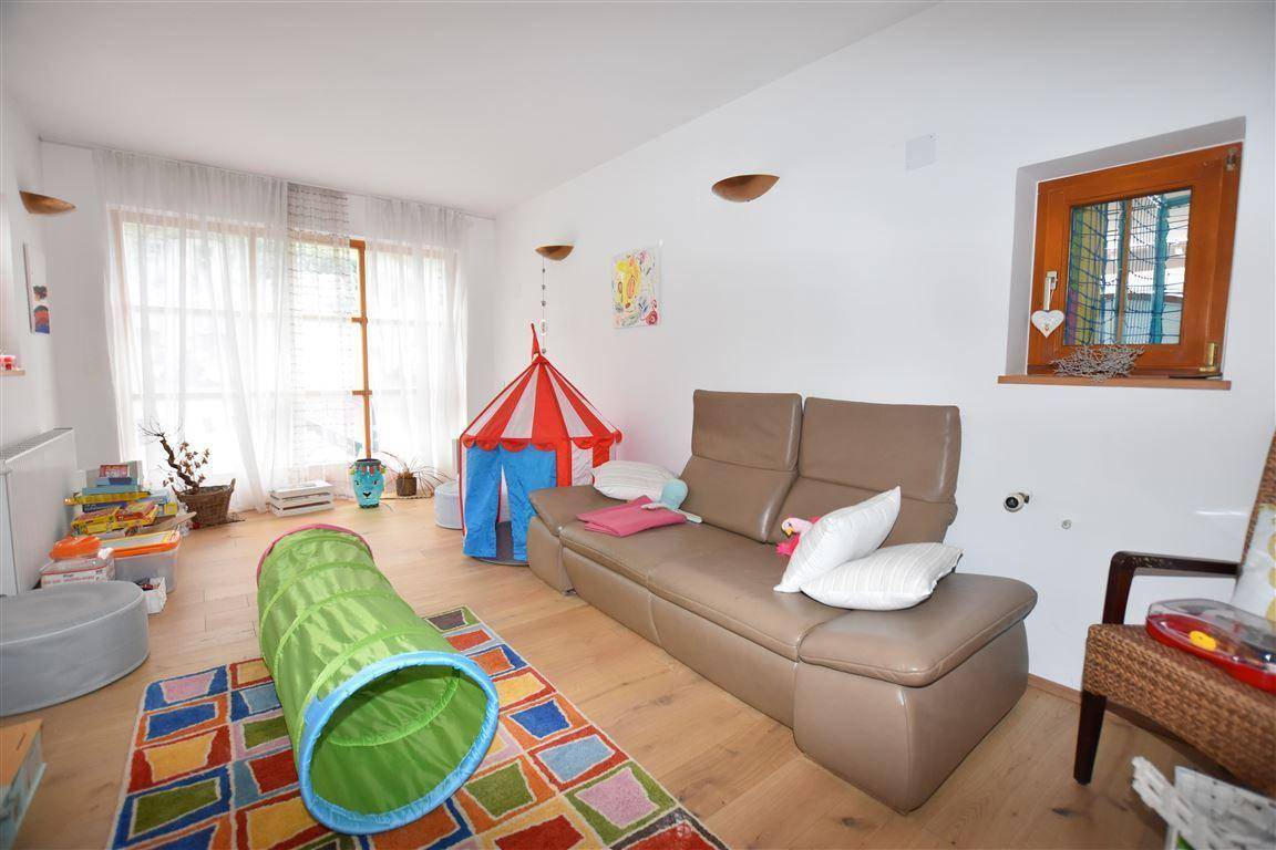 Kinderzimmer mit Spielbereich, Sofa, Holzboden und großen Fenstern für viel Tageslicht.