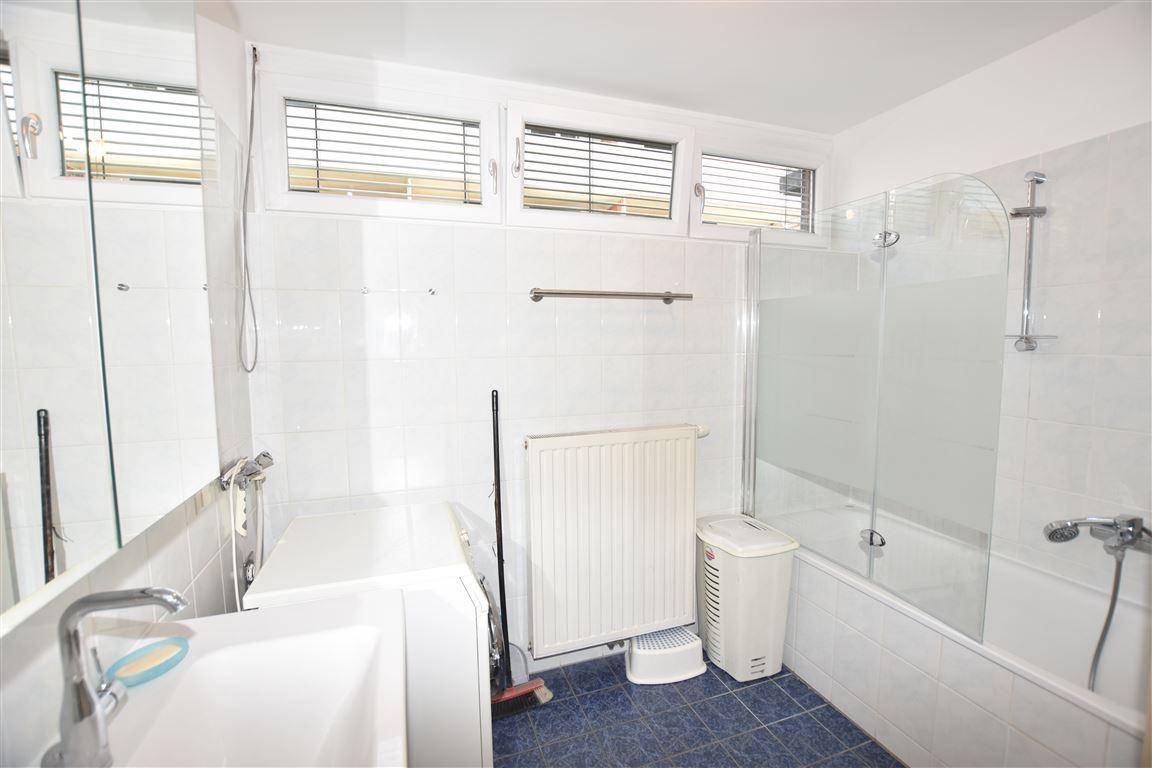 Helles Badezimmer mit Badewanne, Dusche, Waschbecken und Fenster für Tageslicht.