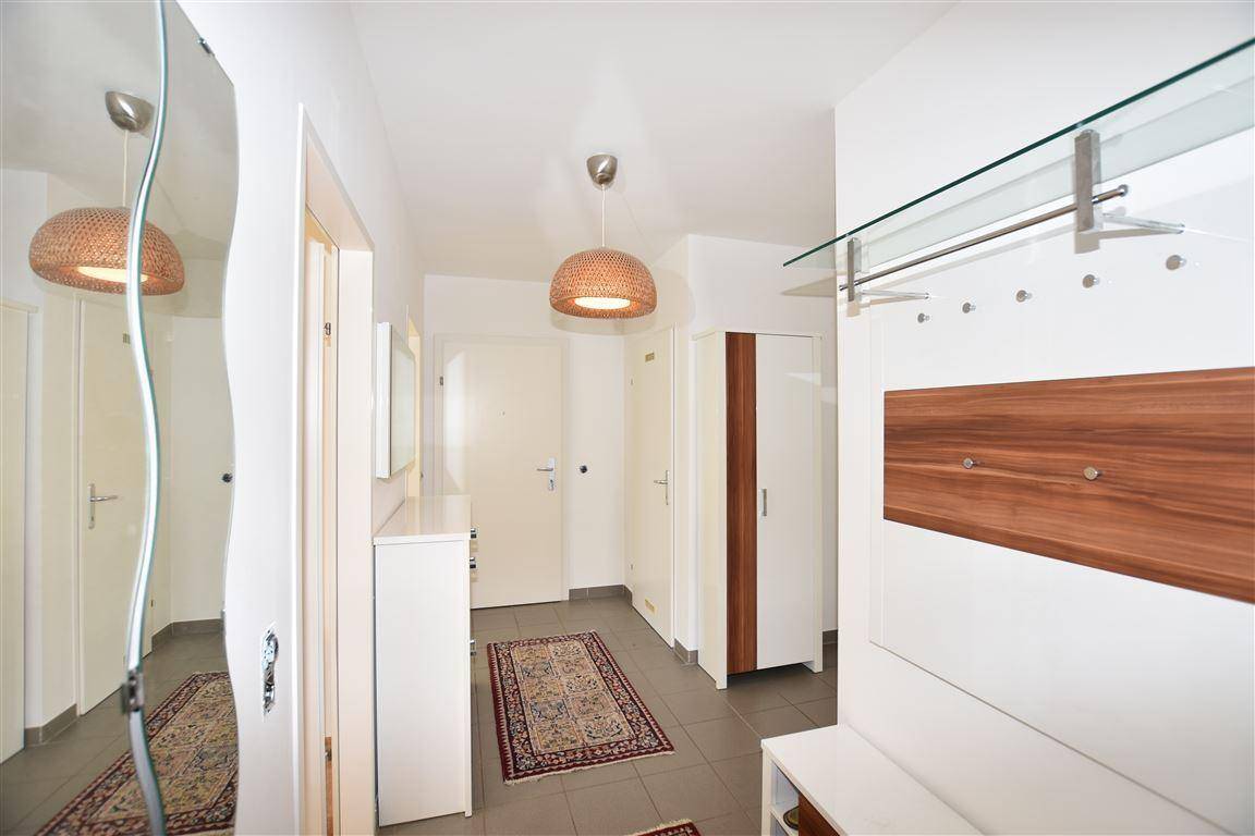 Freundlicher Eingangsbereich mit Fliesenboden, Garderobe und großem Spiegel.