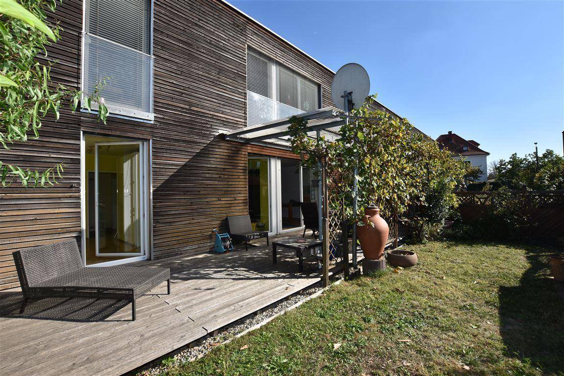 Außenansicht des Hauses mit Holzfassade, Terrasse und gepflegtem Gartenbereich.
