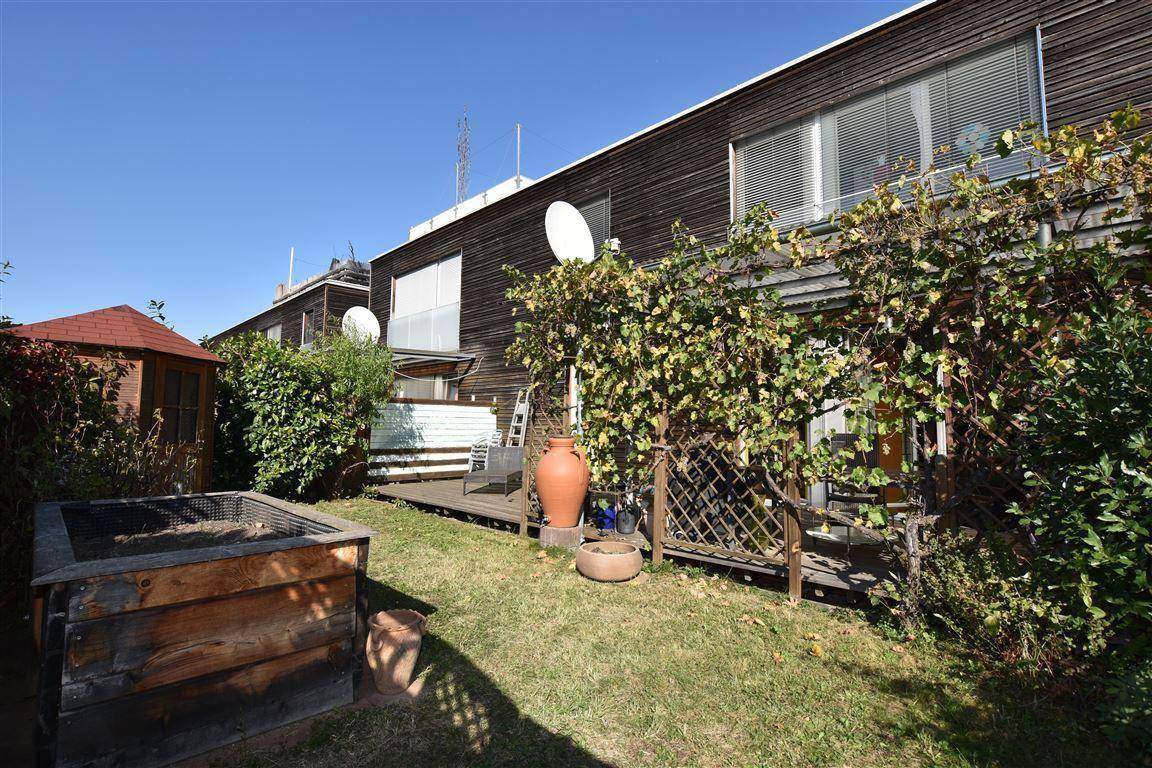 Gepflegter Gartenbereich mit Rasenfläche, Hochbeet und Holzfassade des Gebäudes.