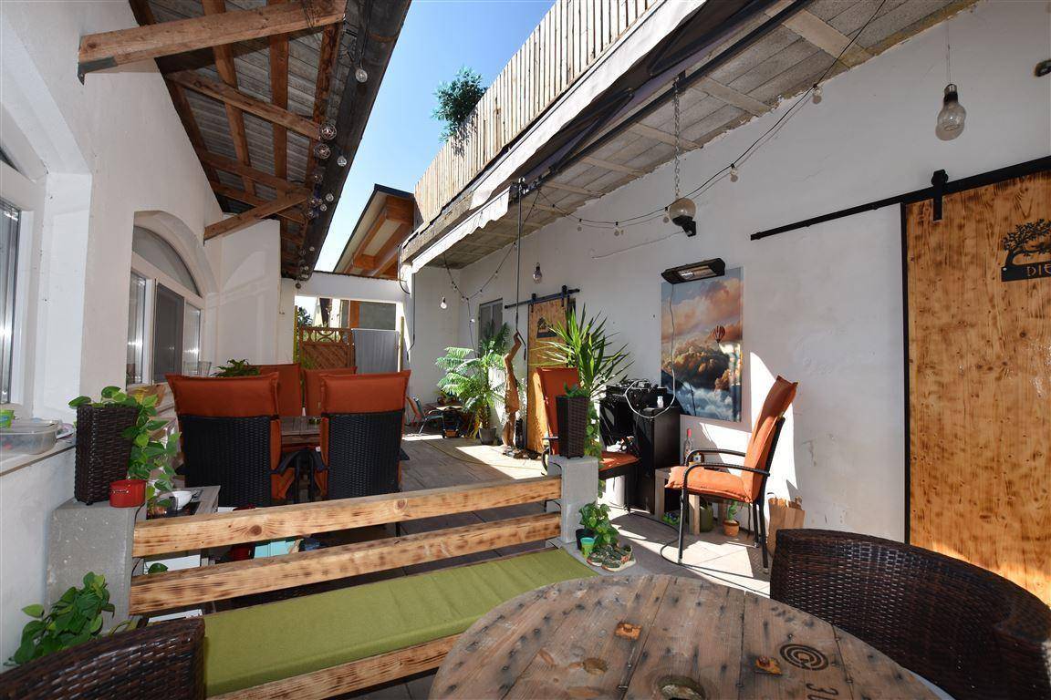 Überdachte Terrasse mit Sitzgelegenheiten und Pflanzen, ideal für entspannte Stunden im Freien.
