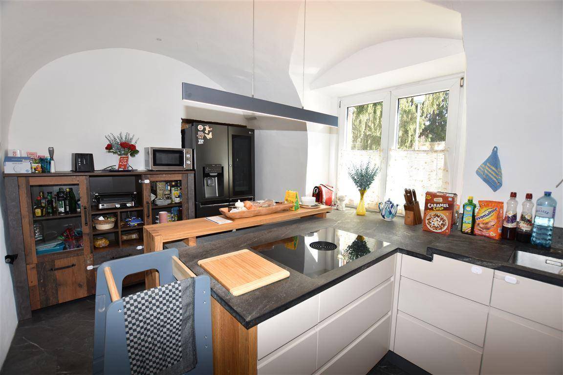 Moderne Küche mit dunkler Arbeitsplatte, Induktionskochfeld und großem Fenster.