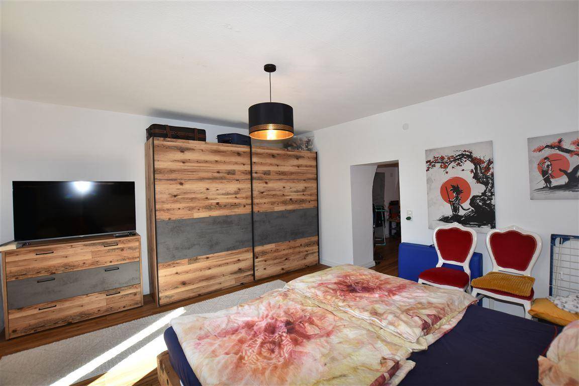 Schlafzimmer mit großem Bett, Holzschrank und moderner Kunst an den Wänden.