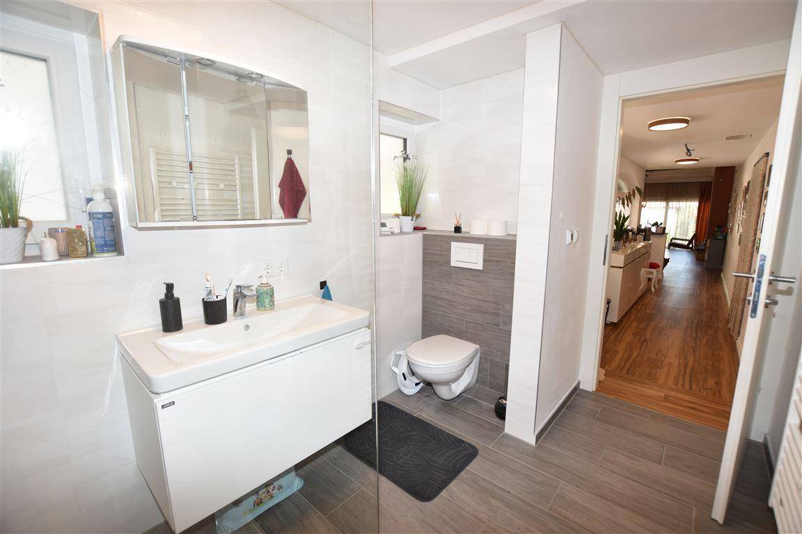 Modernes Badezimmer mit Waschtisch, wandhängendem WC und großformatigen Fliesen.