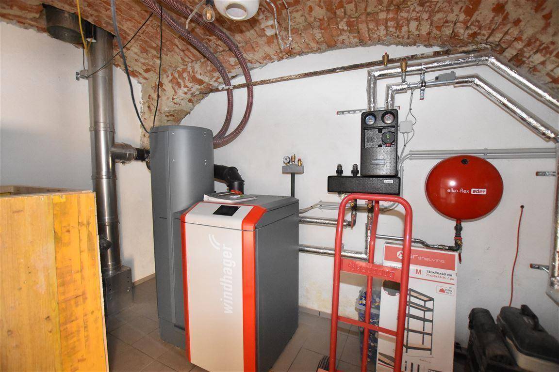 Heizungsraum im Keller mit moderner Pelletheizung und Rohrleitungen.