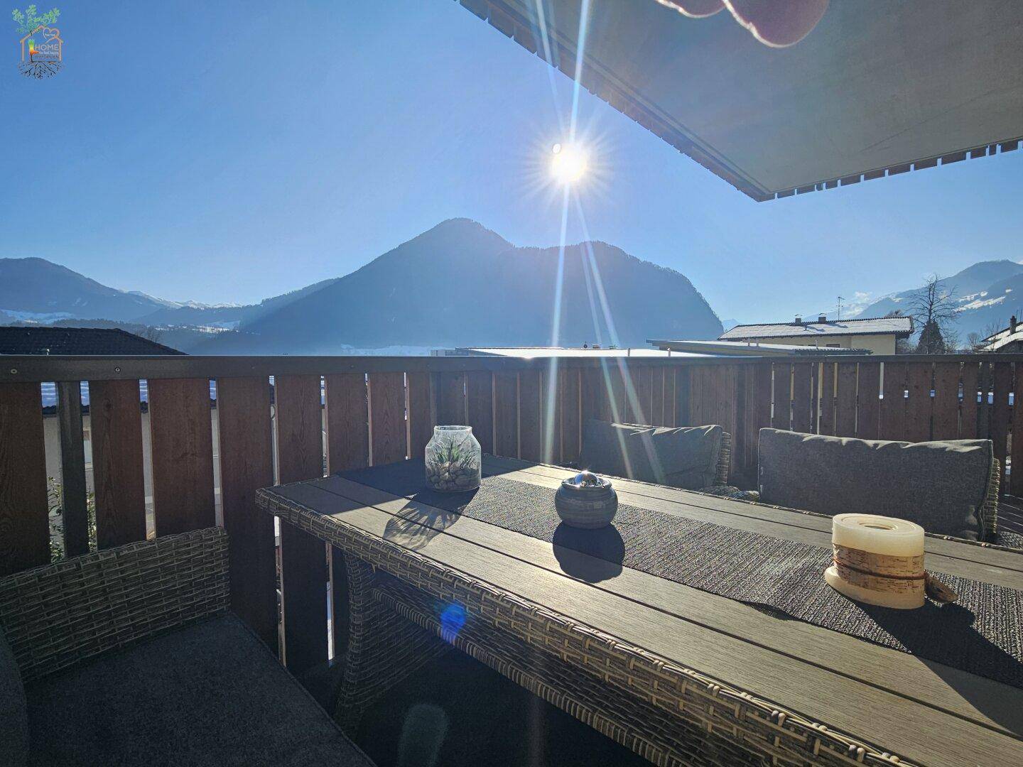 Sonniger Balkon mit Sitzgelegenheiten und atemberaubendem Blick auf den See und die umliegenden Berge.