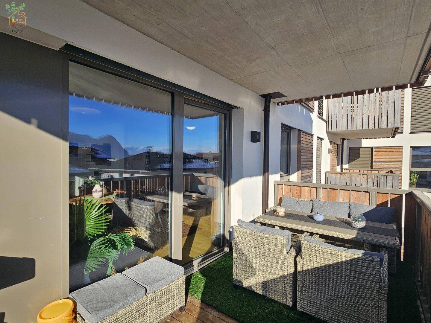 Überdachter Balkon mit Kunstrasen und gemütlicher Sitzecke, ideal für entspannte Stunden im Freien.