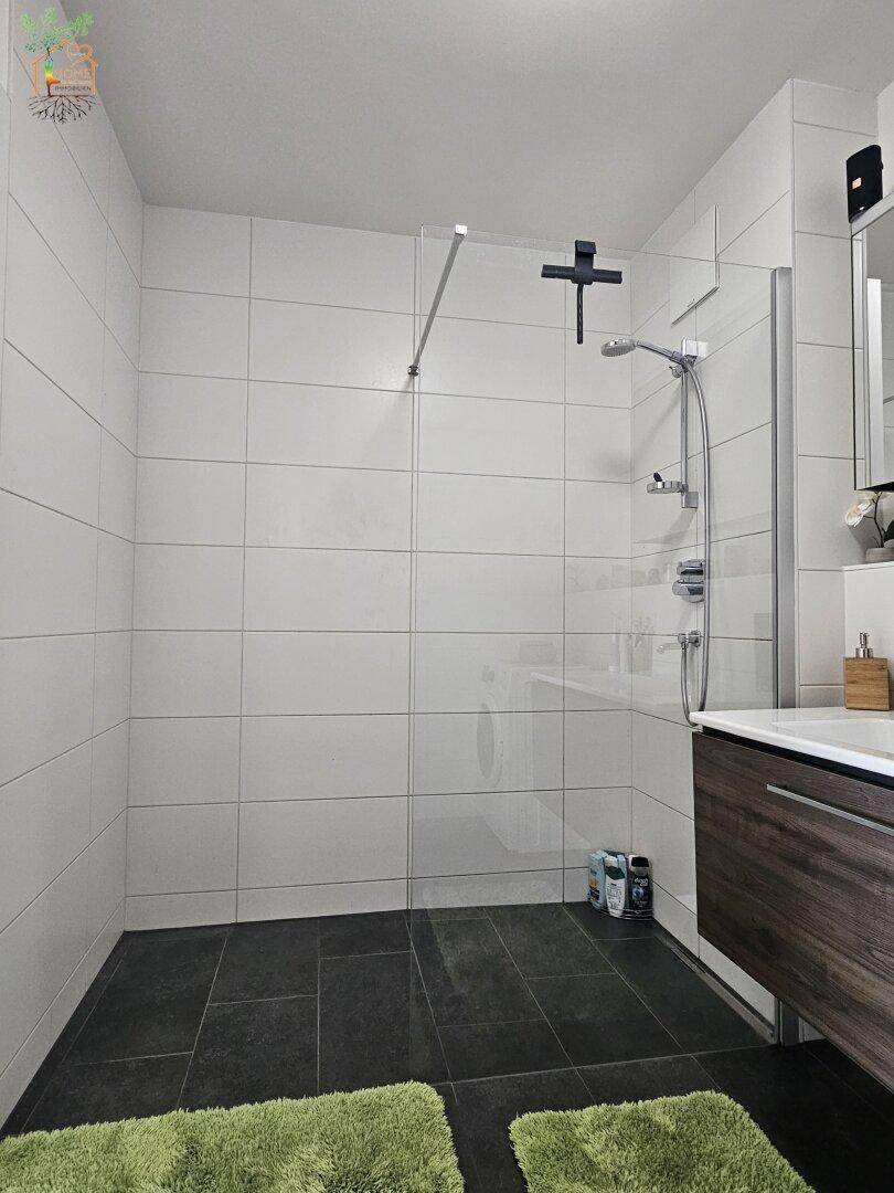 Modernes Badezimmer mit ebenerdiger Dusche und dunklen Bodenfliesen für ein zeitgemäßes Design.