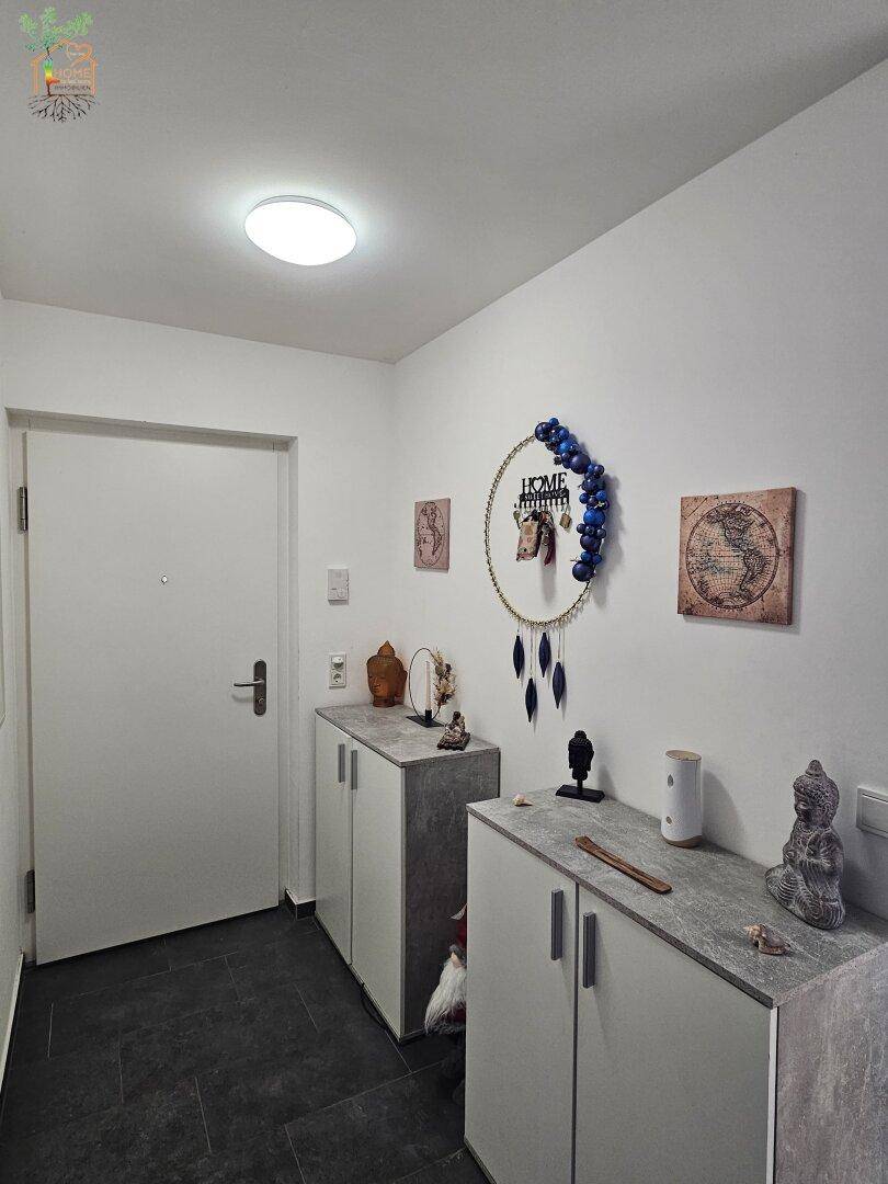 Heller Eingangsbereich mit praktischen Schuhschränken und dunklen Bodenfliesen.