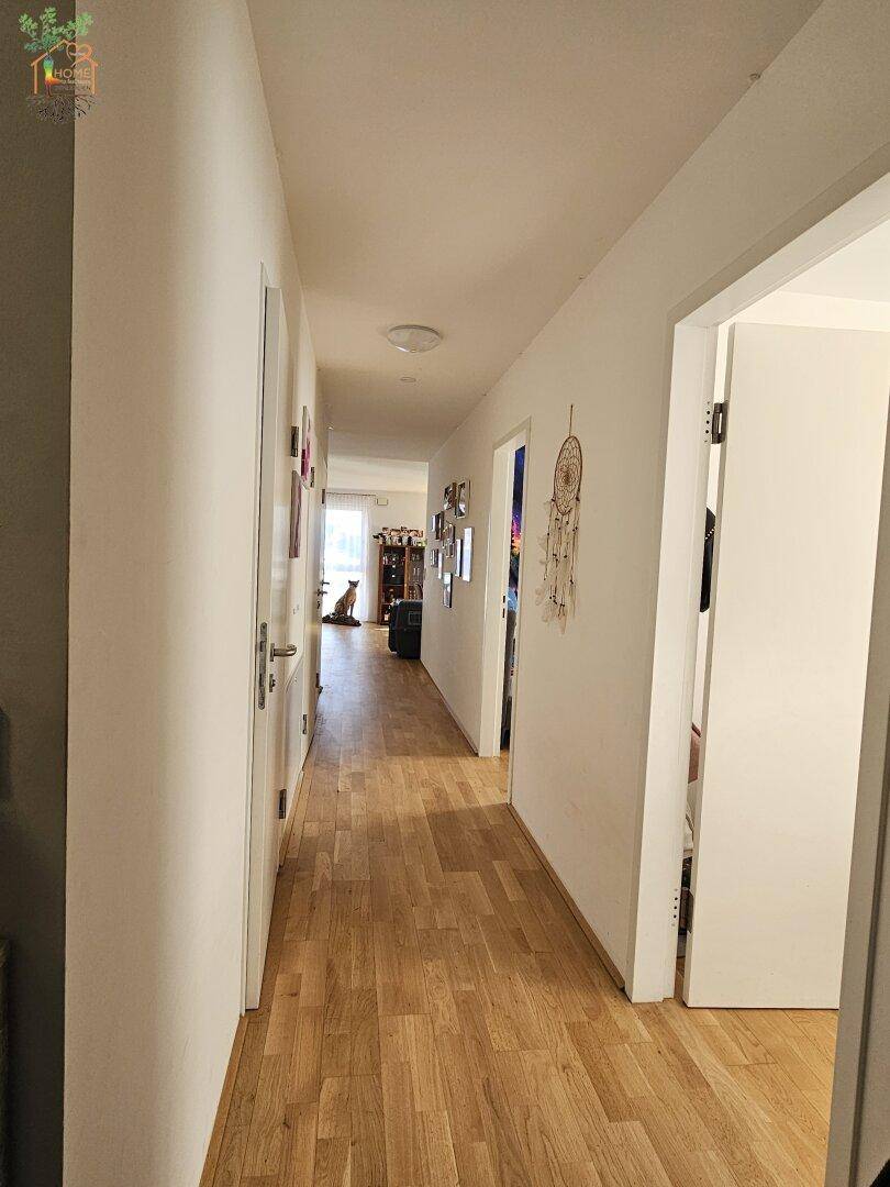Langer Flur mit hellem Holzboden, der verschiedene Räume der Wohnung miteinander verbindet.