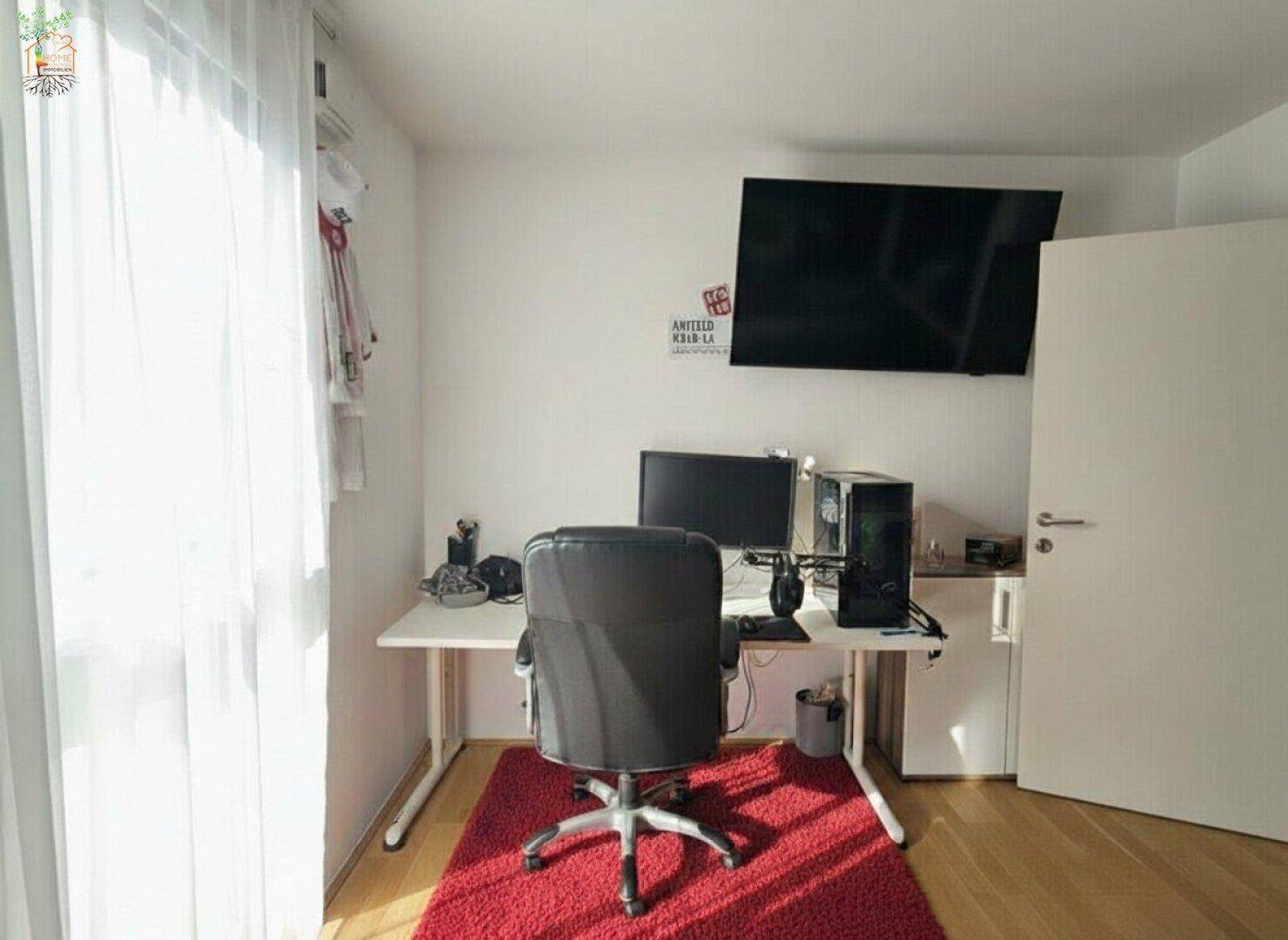 Funktionales Arbeitszimmer mit Schreibtisch, Computer und wandmontiertem Fernseher.