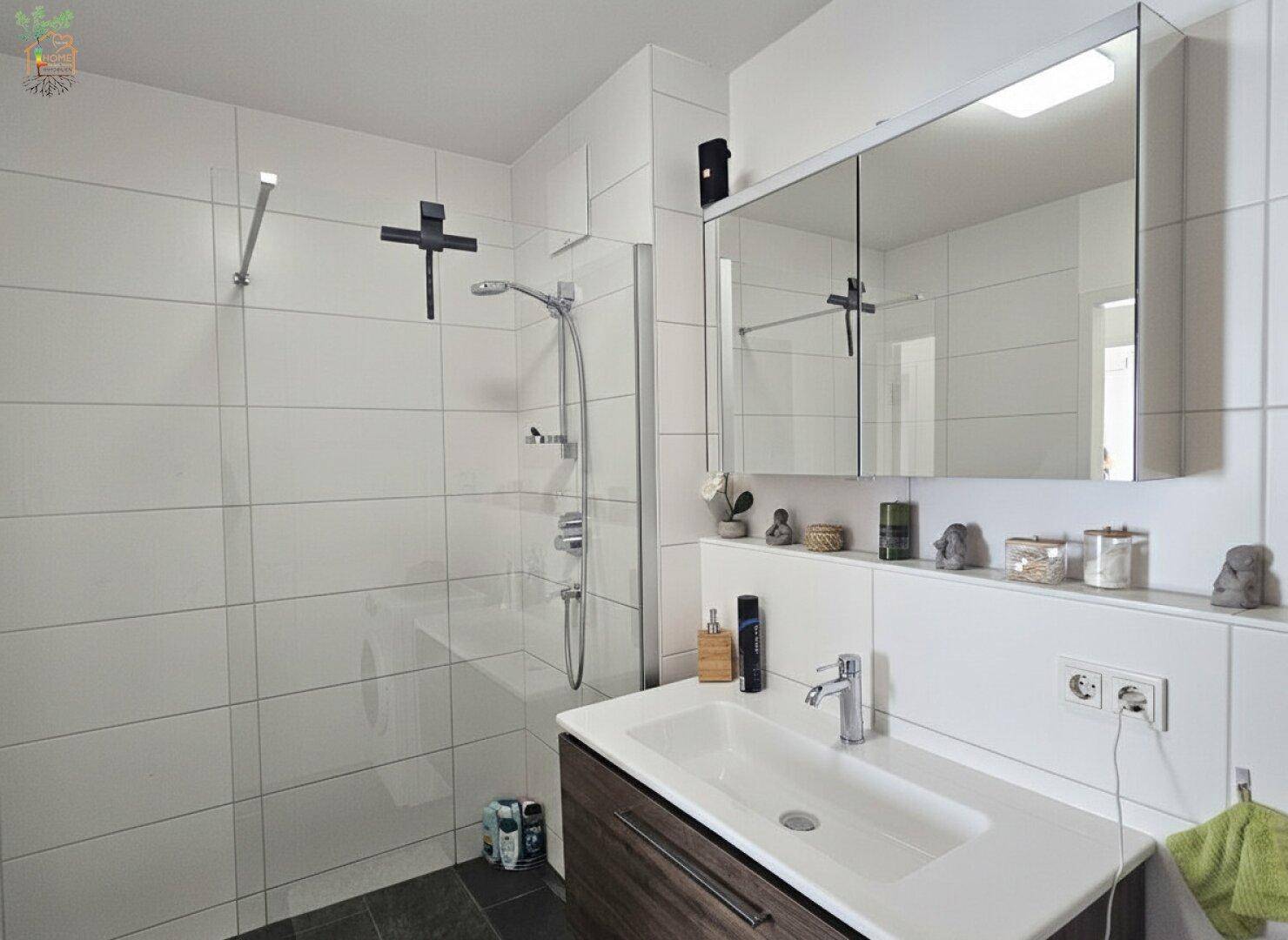 Badezimmer mit modernem Waschtisch, Spiegelschrank und geräumiger Duschkabine.