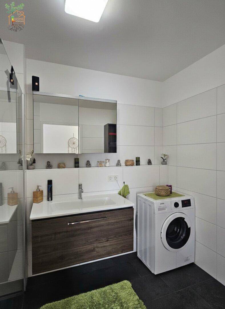 Funktionales Badezimmer mit Waschtisch, Spiegelschrank und integrierter Waschmaschine.