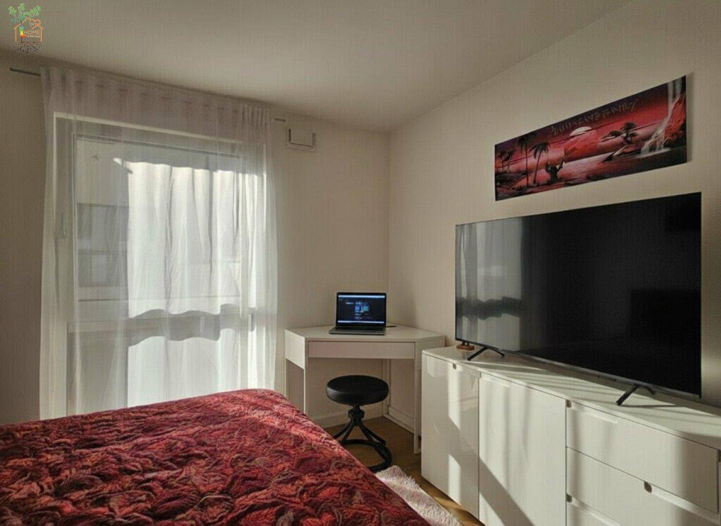 Helles Schlafzimmer mit Bett, Schreibtisch und Fernseher, ideal als Gäste- oder Kinderzimmer.
