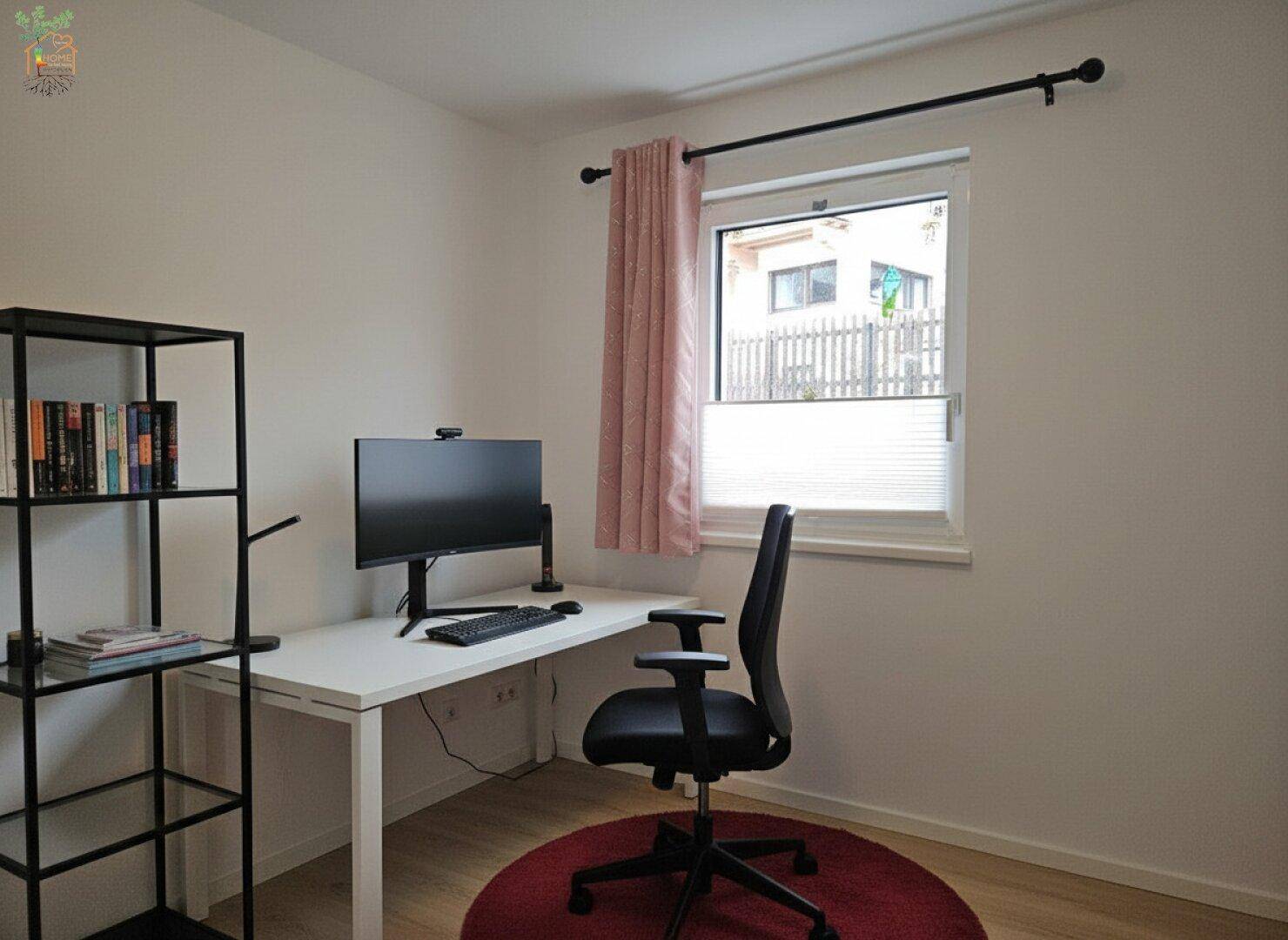 Helles Arbeitszimmer mit Schreibtisch, Bürostuhl und Fensterblick ins Grüne.