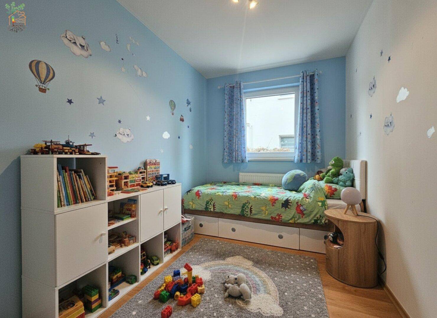 Farbenfrohes Kinderzimmer mit blau gestrichenen Wänden, Einzelbett und Spielzeugregalen.