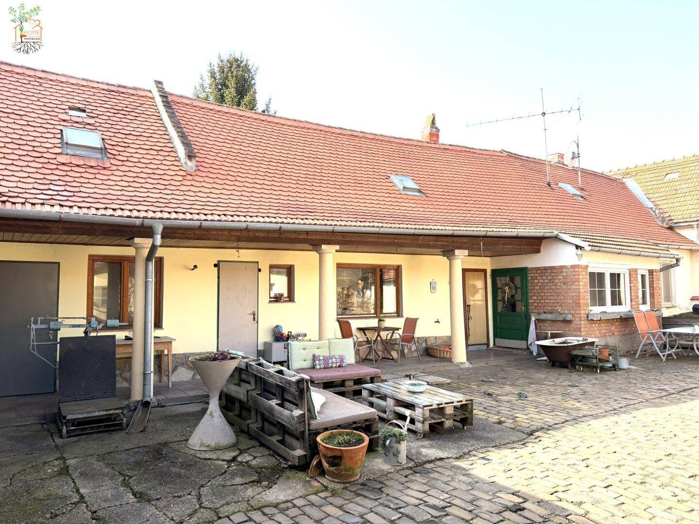 Geräumiger Innenhof mit Pflastersteinen, rustikalen Sitzgelegenheiten und Gebäudefassaden.