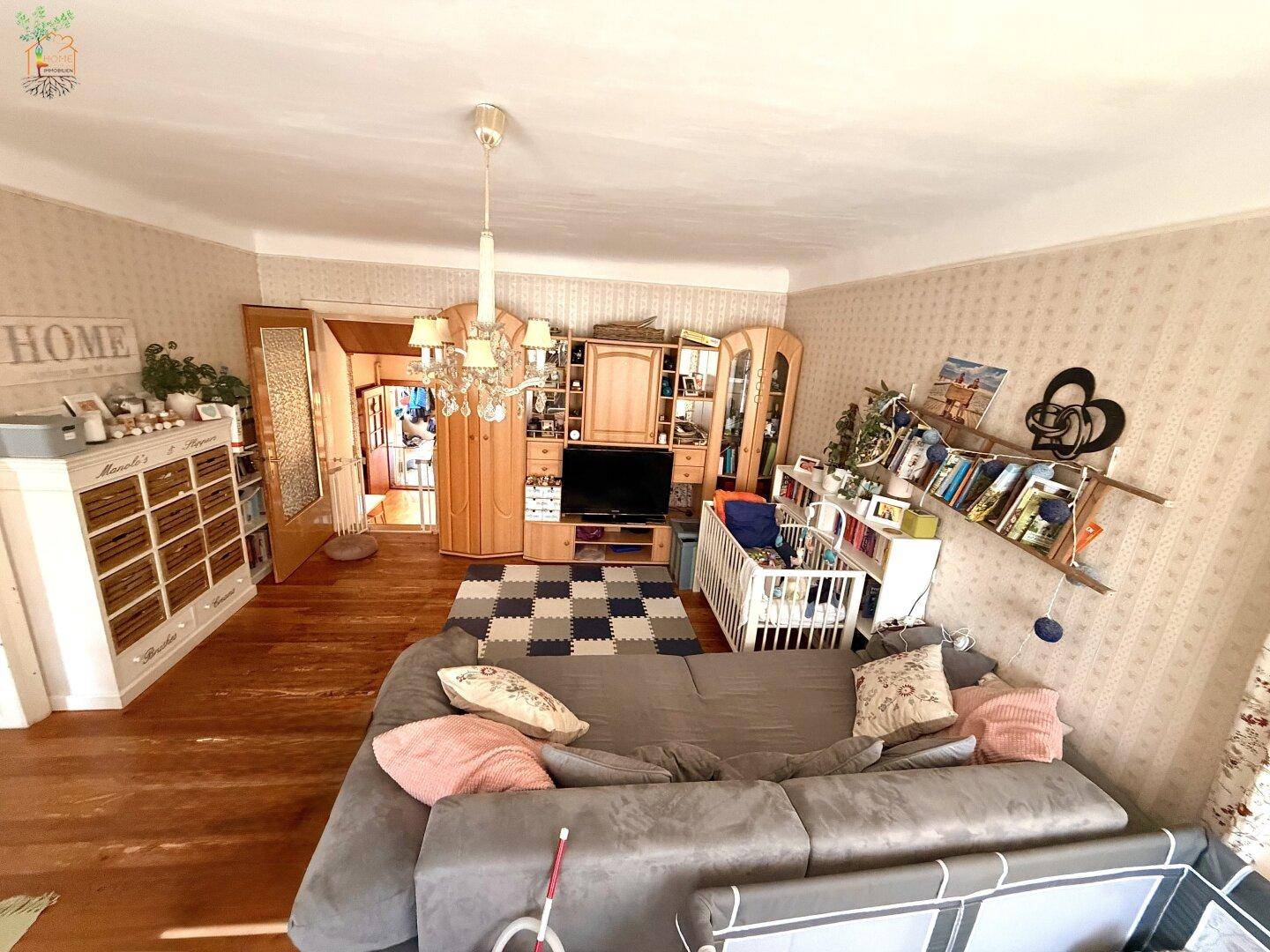Wohnzimmer mit Sofa, TV-Möbeln und Zugang zu einem weiteren Raum, hell und freundlich.