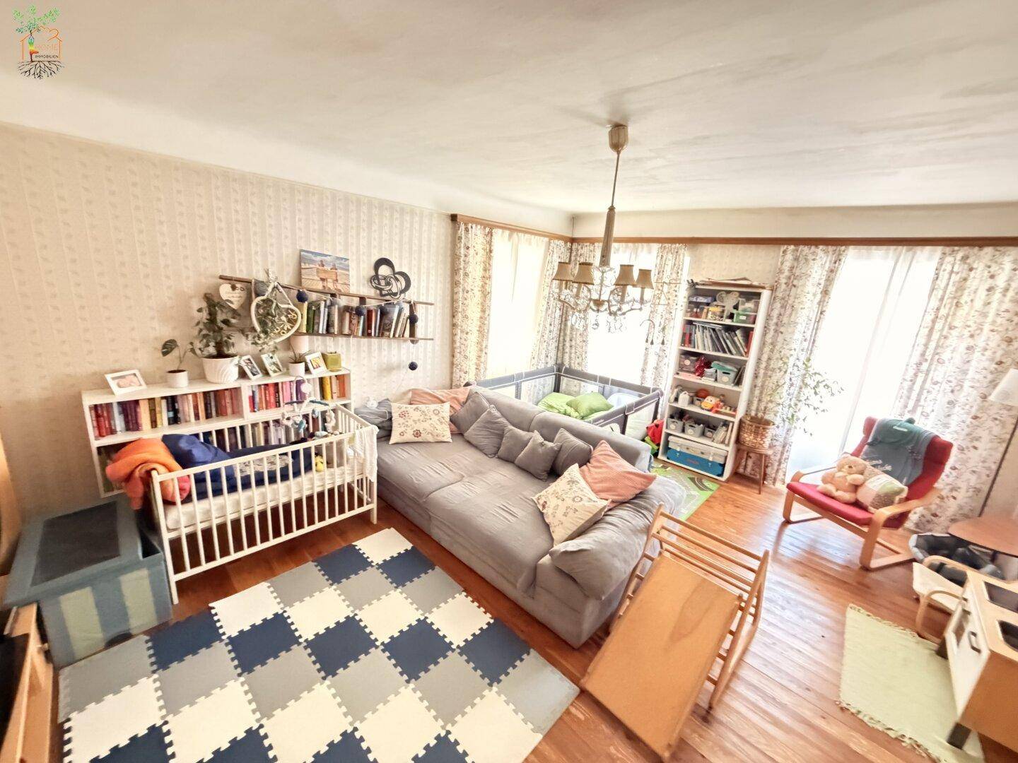 Geräumiges Wohnzimmer mit großem Sofa, Bücherregalen und Spielbereich für Kinder.