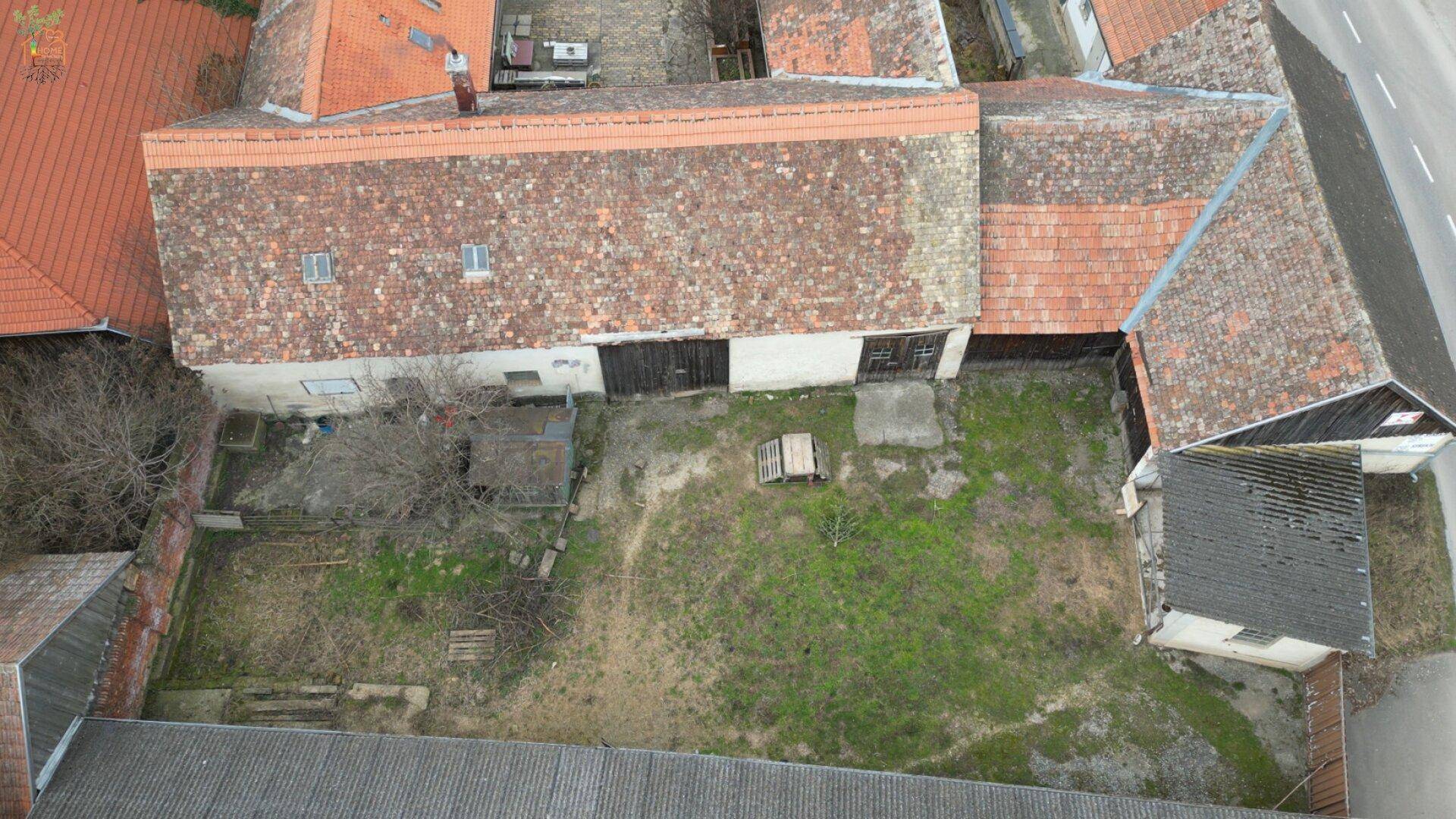 Vogelperspektive auf einen Innenhof und Gartenbereich eines ländlichen Anwesens mit Nebengebäuden.