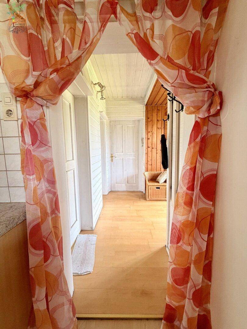 Heller Flur mit Holzboden und Garderobe, der verschiedene Räume miteinander verbindet.