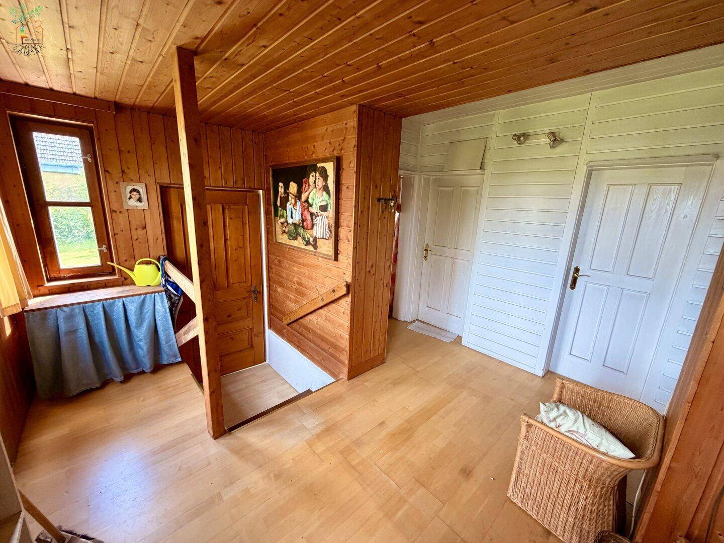 Geräumiger Flur mit Holzvertäfelung, Holzboden und Zugang zu weiteren Zimmern.