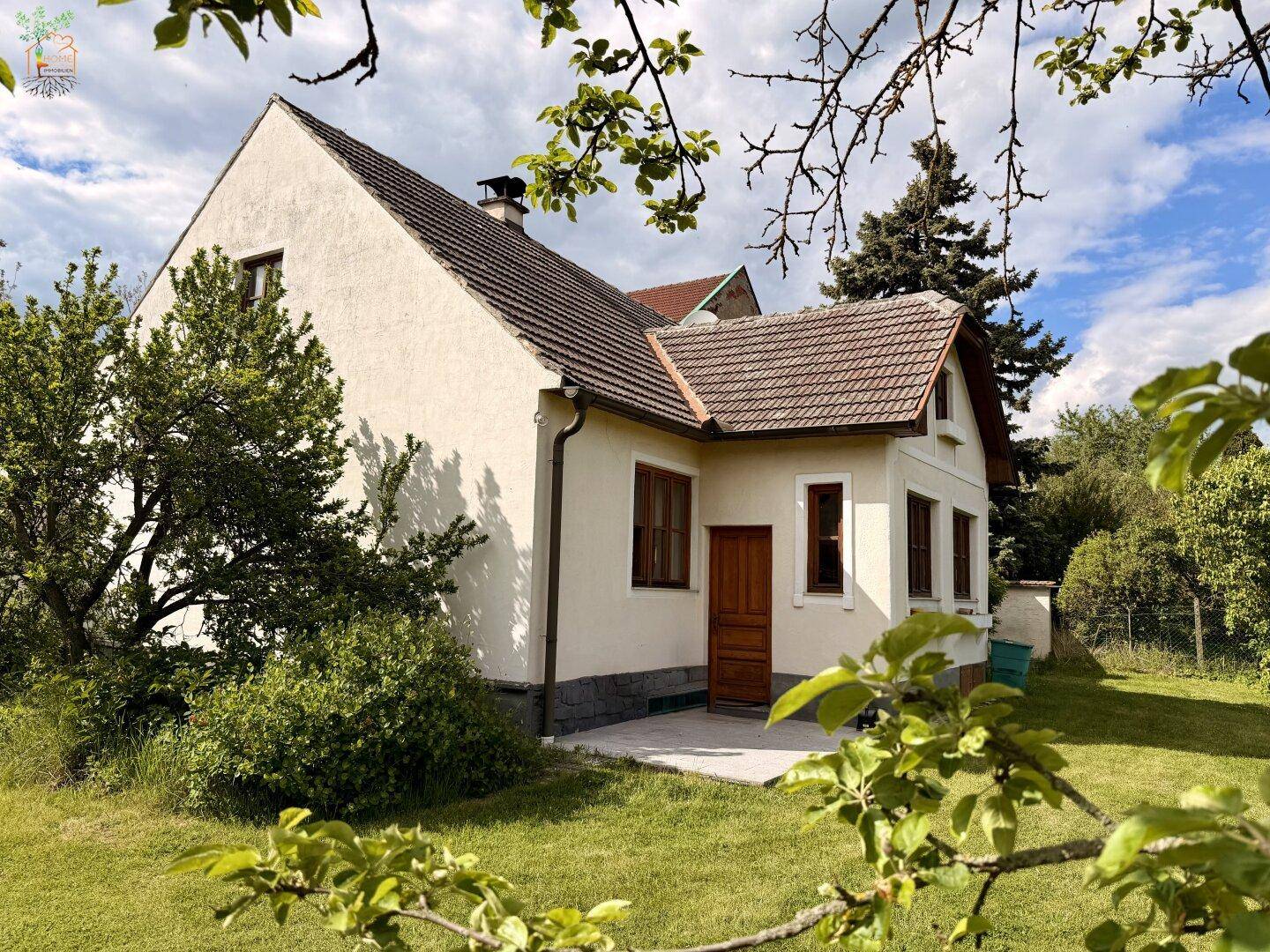 Seitenansicht des Hauses mit kleiner Terrasse und Zugang zum weitläufigen Gartenbereich.