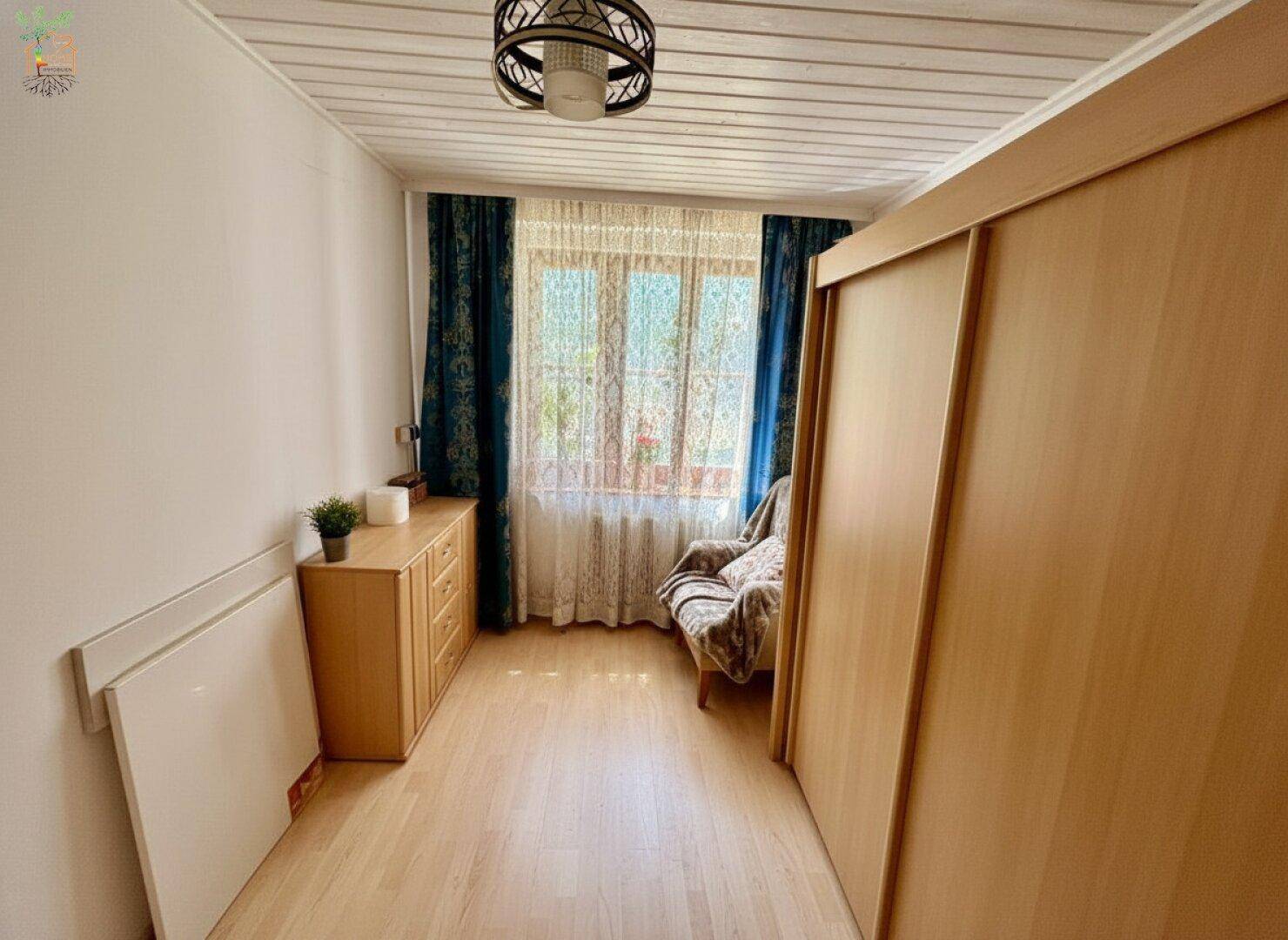 Gemütliches Schlafzimmer mit Holzdecken, Parkettboden und einem großen Kleiderschrank.