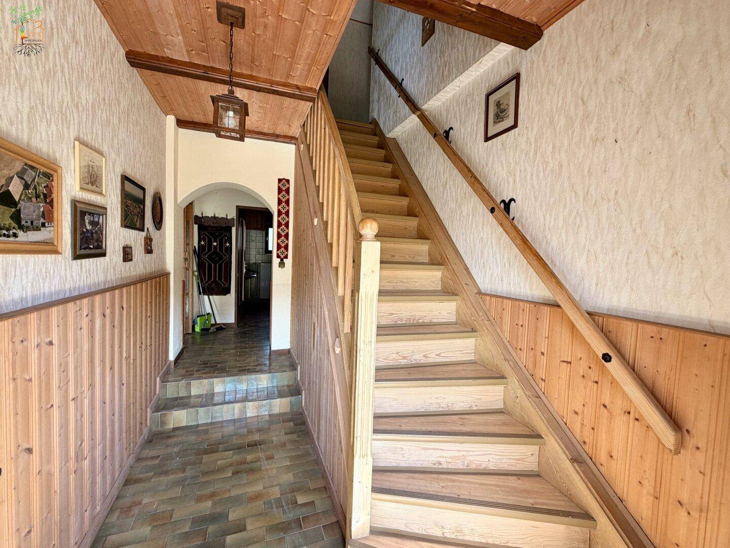 Geräumiger Flur mit Holzvertäfelung, Holzbalkendecke und Treppe zum Obergeschoss.