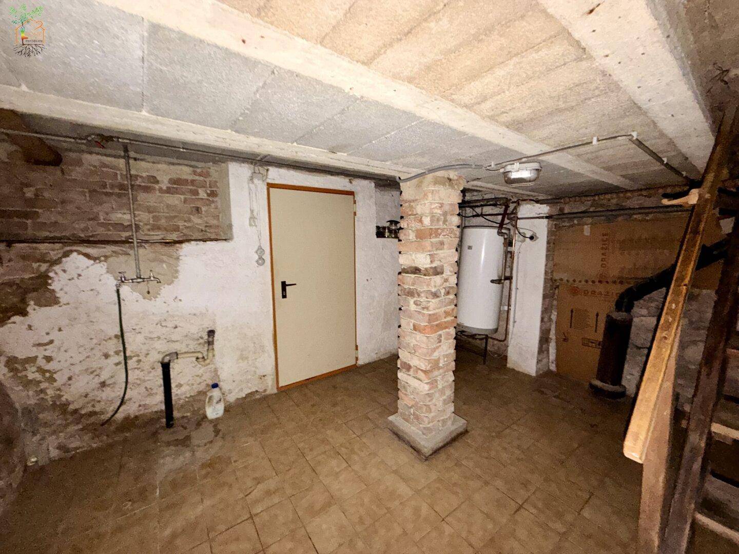 Kellerraum mit Fliesenboden, unverputzten Wänden und Warmwasserboiler.