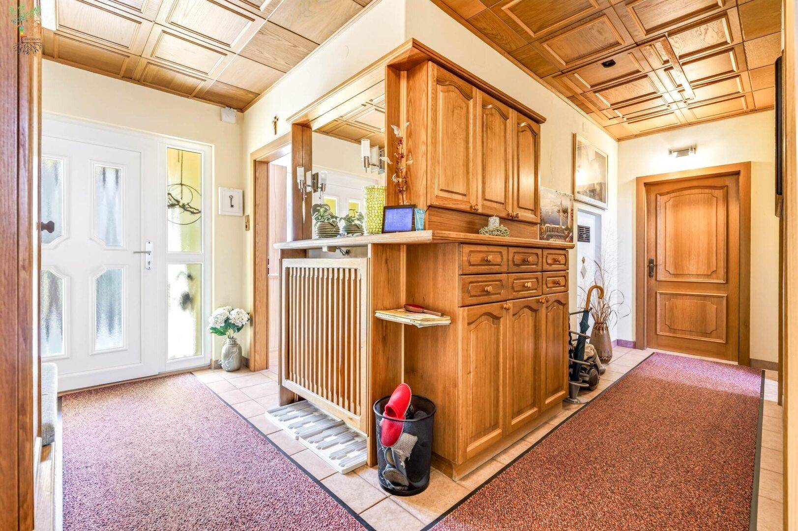Traditioneller Eingangsbereich mit Holzvertäfelung, Einbauschrank und gemustertem Teppichboden.