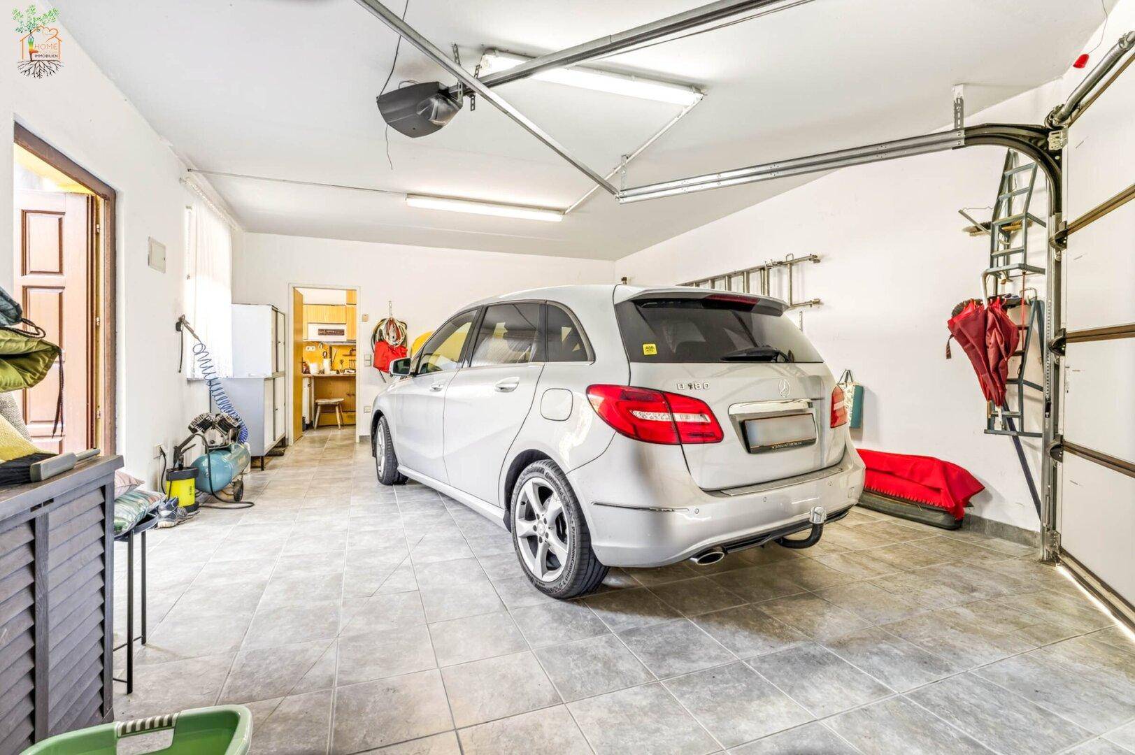 Geräumige Garage mit Fliesenboden, automatischem Tor und ausreichend Platz für ein Fahrzeug.