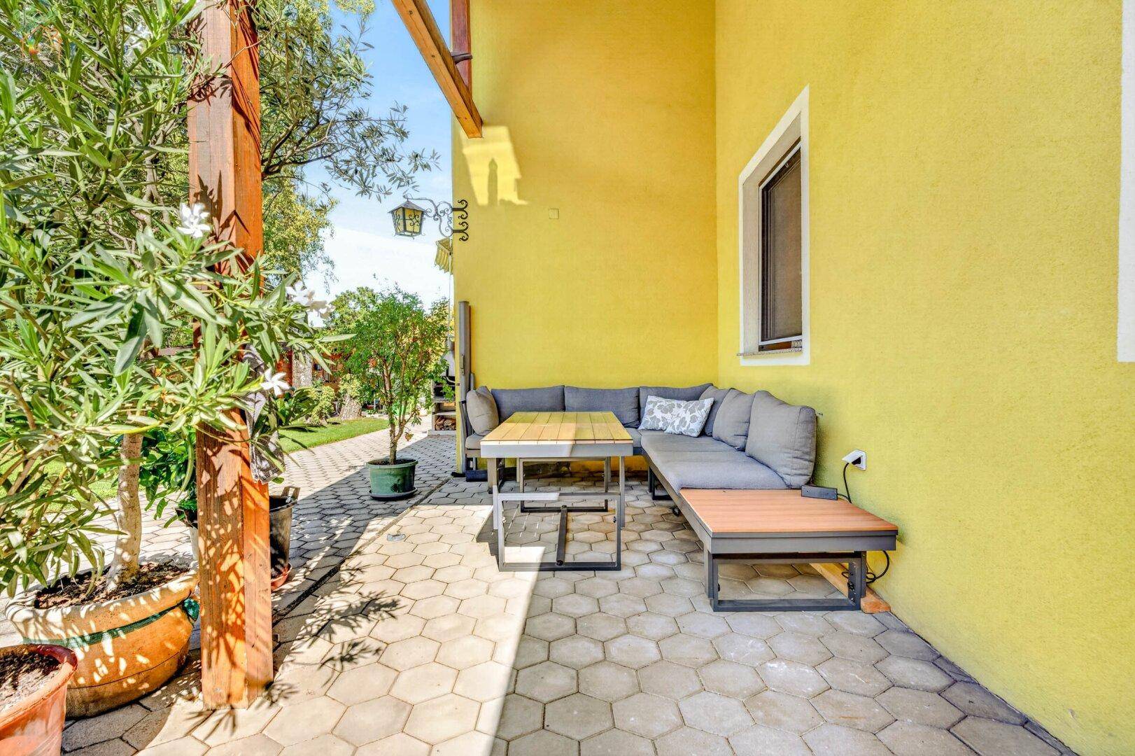 Überdachte Terrasse mit bequemen Lounge-Möbeln, ideal für entspannte Stunden im Freien.